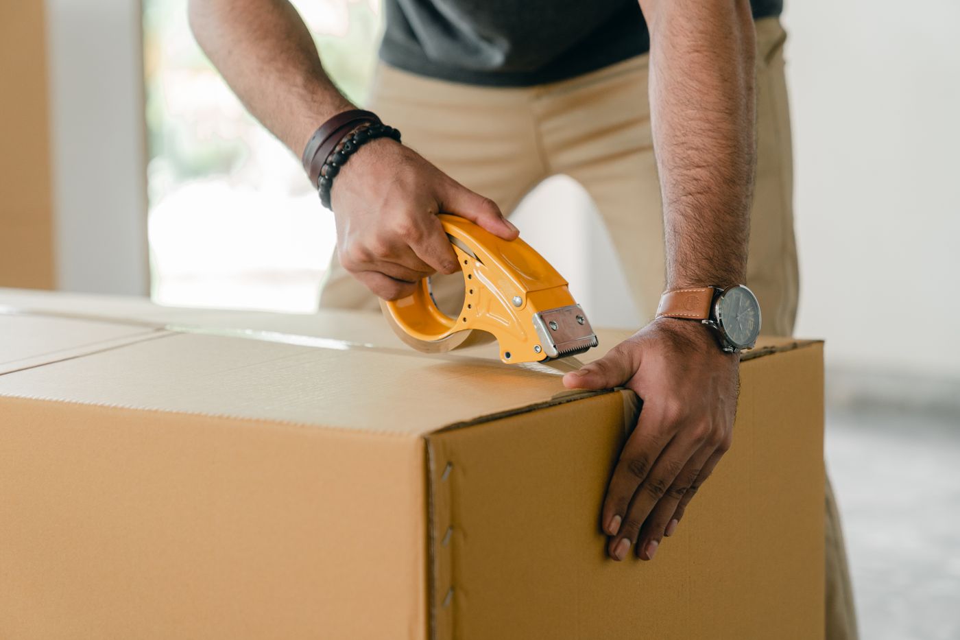 Manos sellando con cinta una caja de cartón antes de una mudanza