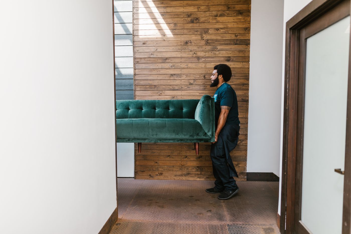 Persona transportando un sillón verde dentro de un inmueble durante un flete